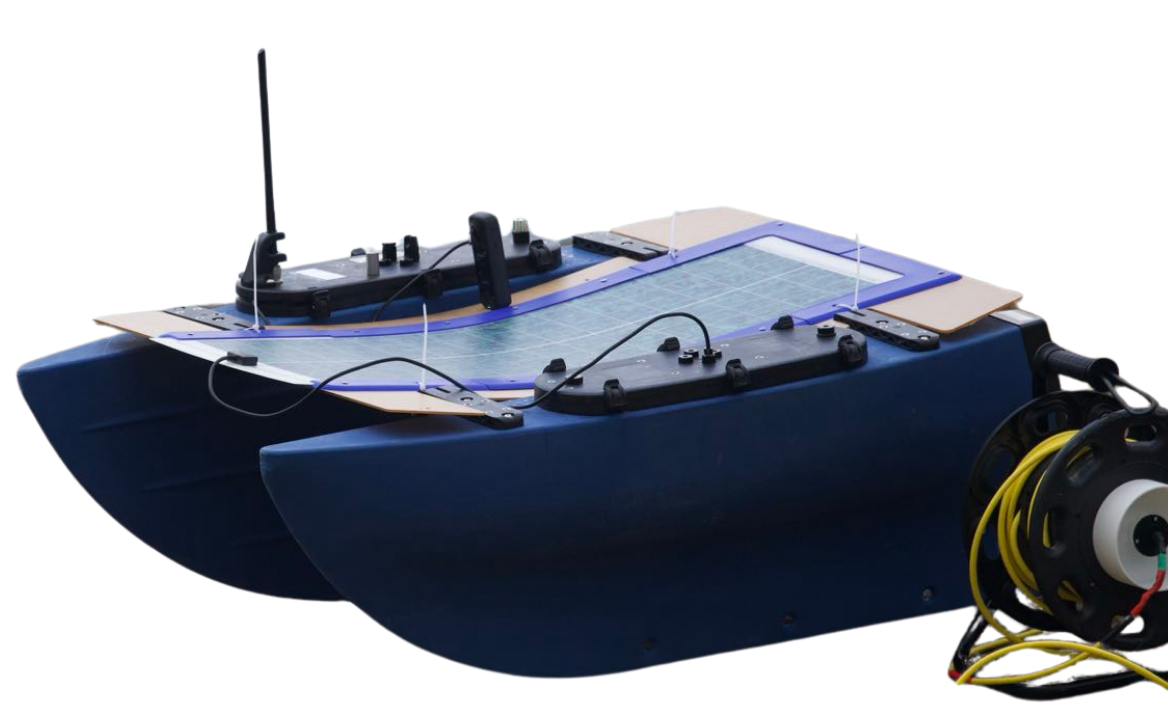 Blue twin-hull surface vessel with a solar-panel deck, antenna and tether reel
